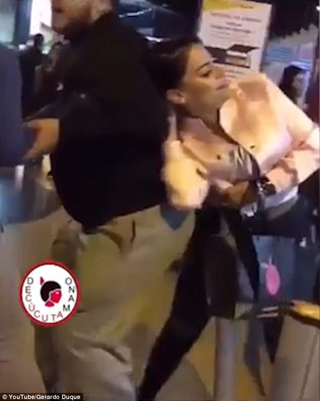 She hurls insults at her cheating husband (centre) while still holding on to his lover's locks
